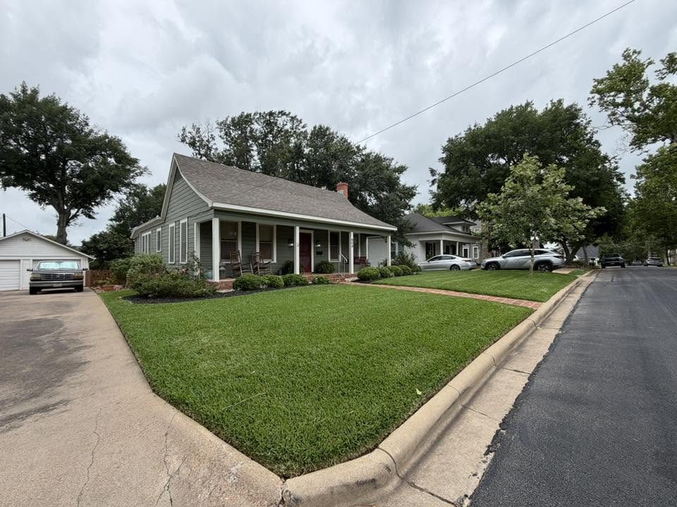 Corner-lot lawn with crisp mowing stripes and clean beds