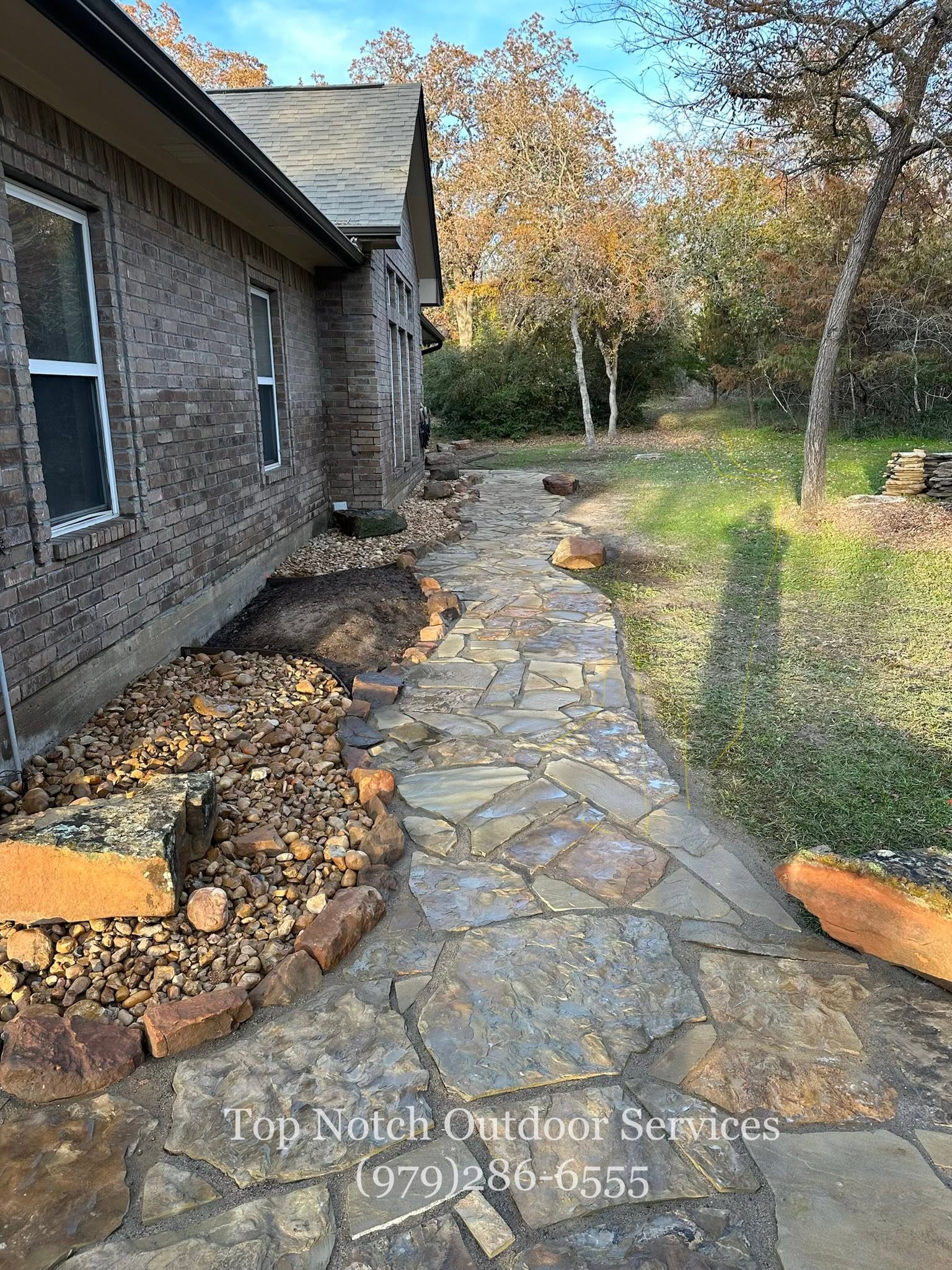 Finished flagstone path with river-rock border in fall