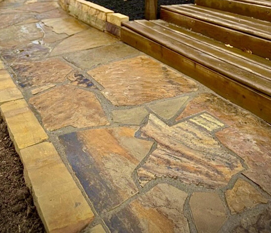 A flagstone hand-cut in the shape of Texas, set into a curved walkway beside deck steps